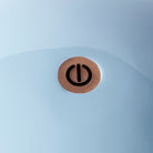 Close-up of the power button on the top of the pale blue lacquered lamp