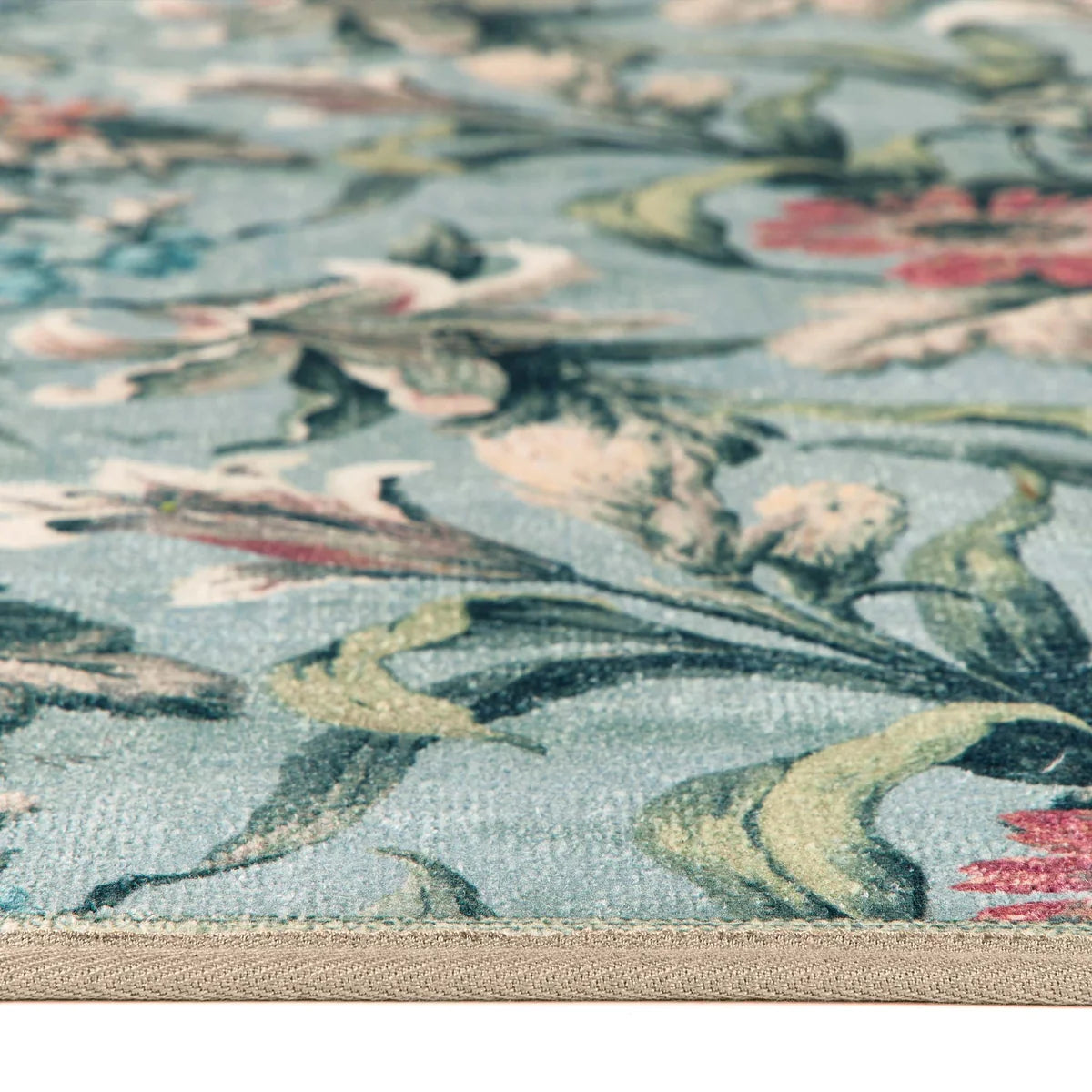 Close-up of the soft blue floral rug texture and stitched edge