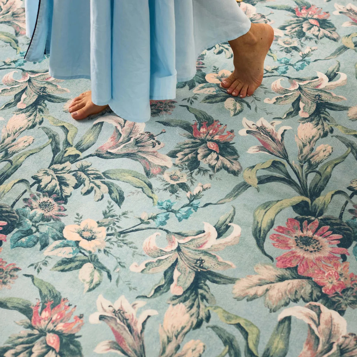 Close-up of feet on the soft blue floral rug showing pile detail