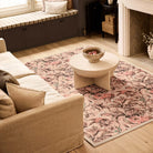 Lys Pink rug styled in a living room beside a neutral sofa and round coffee table.
