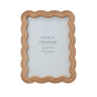 Natural brown wooden photo frame with a unique wavy scalloped edge design for five by seven inch photographs.