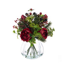 Artificial red roses and dark berries in a ribbed glass vase against a white background.