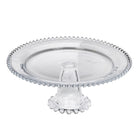 Clear glass pedestal cake stand with beaded edge detailing on a white background