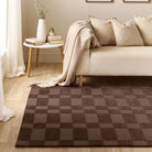 Origins Soho Chocolate rug styled in a living room beside a cream sofa and wooden floor.