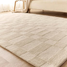 Low angle view of the Soho Ivory Rug styled on a light wood floor at the foot of a bed.