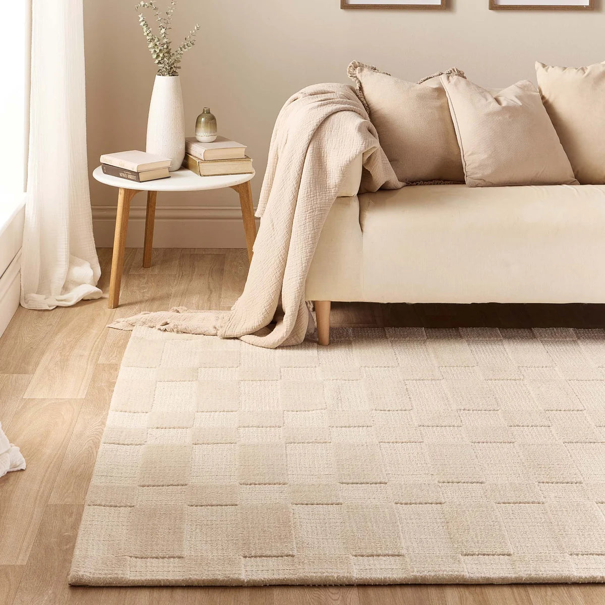 The Soho Ivory Rug styled in a neutral living room setting with a cream sofa and side table.