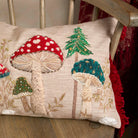 Close-up of the textured embroidery on the toadstool cushion showing the green trees and red fungi details.