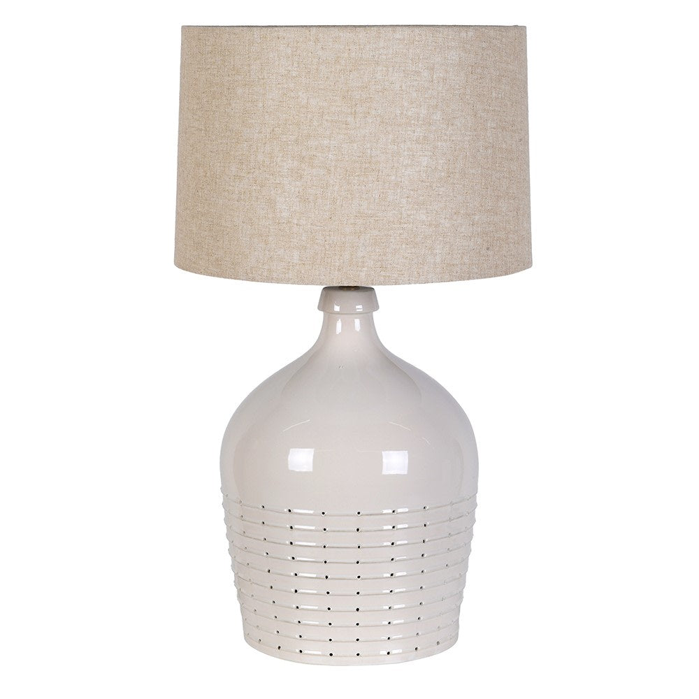 Pale off-white ceramic table lamp with a pierced dotted base and natural linen shade against a white background.