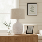 The Dotted Table Lamp styled on a light oak sideboard next to a small glass vase and framed picture.