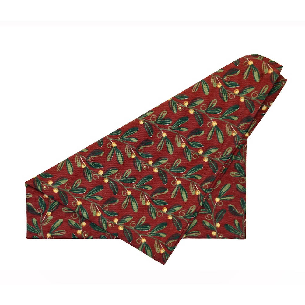 Red cotton napkin with green mistletoe print folded into a triangle shape