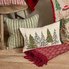 Festive Winter Woods cushion styled in a home setting on a red rug beside a wooden stool and striped cushion.