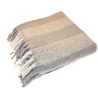 Folded birch coloured wool blend throw with wide stripes and white lambs tail fringing