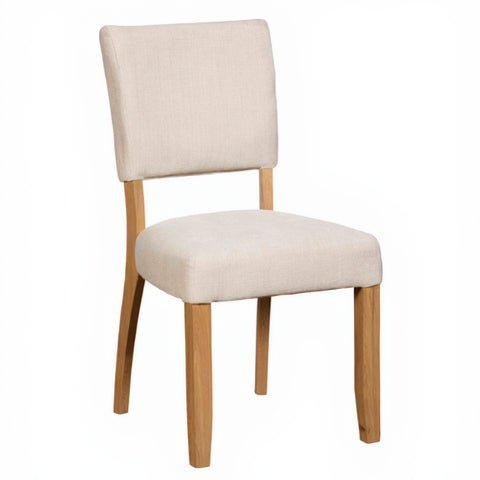 Three-quarter view of the Burford upholstered dining chair showing natural oak legs and neutral fabric