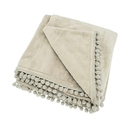 Folded linen-coloured fleece throw with decorative pom-pom braid edging.