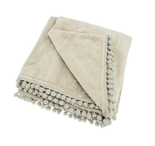 Folded linen-coloured fleece throw with decorative pom-pom braid edging.