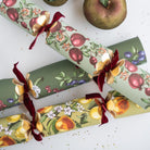 Vintage-style Christmas crackers with pomegranate and cherry patterns scattered on a white surface.