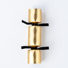 Single gold chocolate truffle cracker viewed from above against a plain white background.