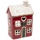 Red ceramic tea-light house with a white snowy roof, heart-shaped window, and green door detail.
