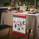 Red and white striped cotton table runner with Nutcracker ornament illustrations on a festive dining table.