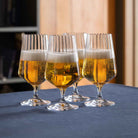 Lifestyle shot of four ribbed small beer glasses filled with golden ale in a domestic setting.