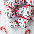 A pile of petite confetti dot crackers scattered on a white surface with red candy canes.