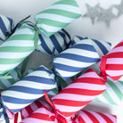 Close-up of diagonal striped Christmas crackers in blue, green, and red with matching ribbons.