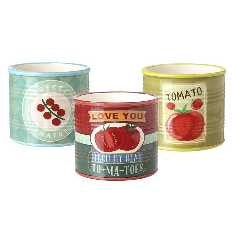 Three assorted ceramic tomato pots in blue, red, and green with vintage-style labels.