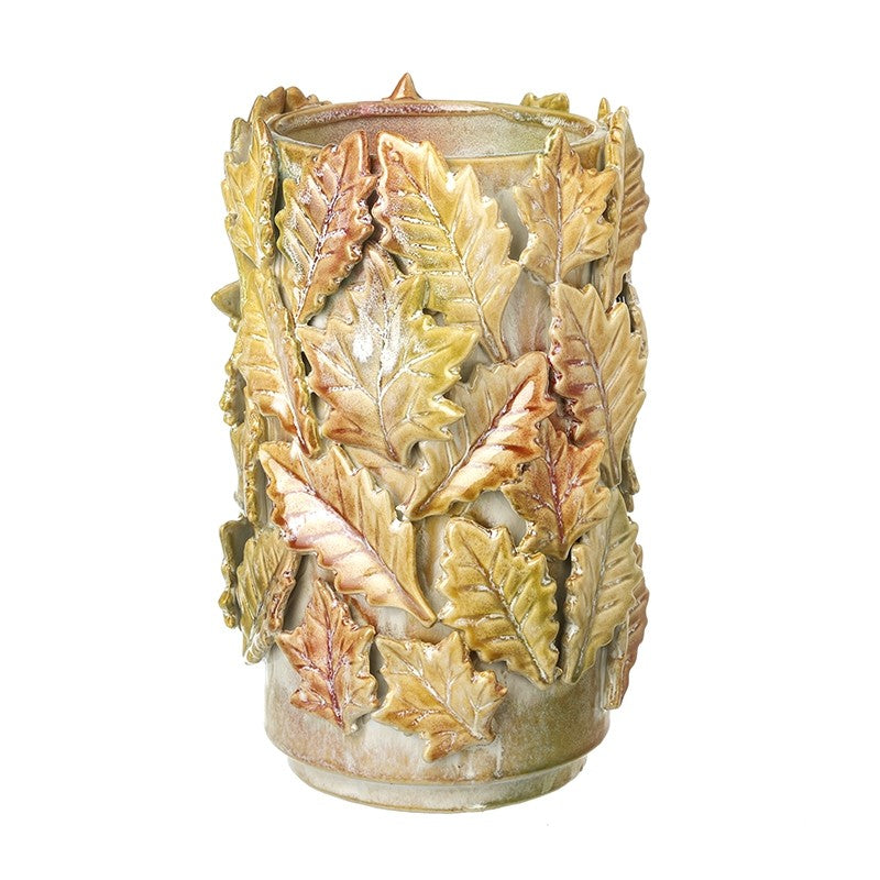 Cylindrical ceramic vase covered in textured, overlapping autumn leaves in shades of green and brown.