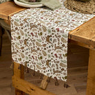 Cotton woodland table runner with tassels styled on a rustic wooden dining table.