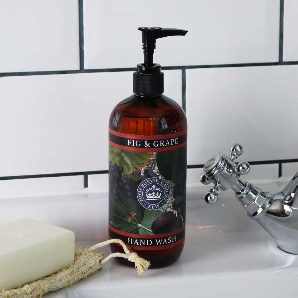 Fig and Grape hand wash bottle styled on a white tiled bathroom sink next to a white soap bar and natural loofah.