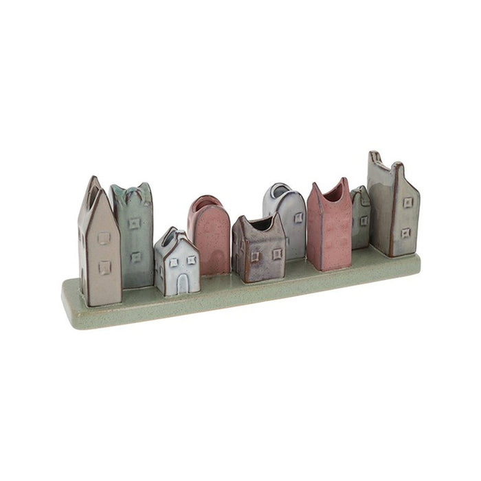 Handcrafted ceramic house-shaped vase with nine stem openings in muted multicoloured glazes on a green base.
