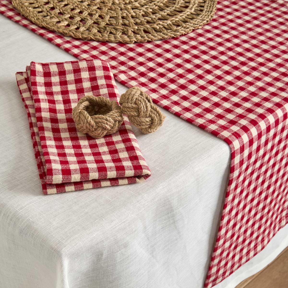 Red gingham napkins and matching table runner styled on a white linen tablecloth with natural rope napkin rings.