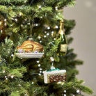 Whimsical glass turkey bauble styled on a green Christmas tree alongside a champagne bottle ornament.
