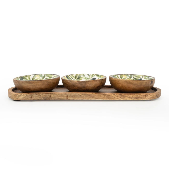 Three small mango wood dipping bowls with olive pattern interiors resting on a long wooden tray