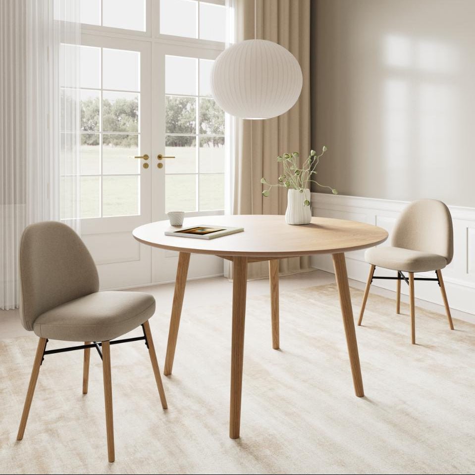 Two Sophia dining chairs styled around a circular oak dining table in a bright, modern room