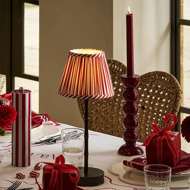 A festive dining table setting featuring the cherry bobbin candlestick with a lit burgundy candle.