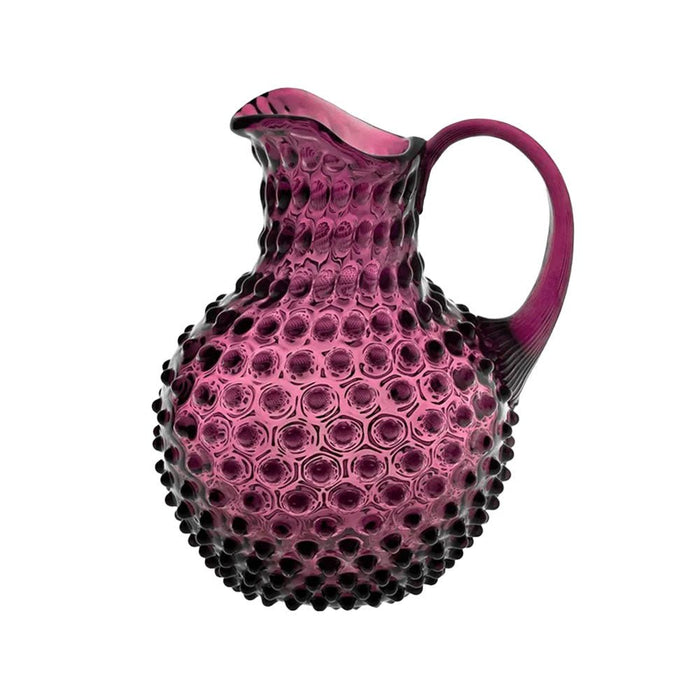 A vibrant violet glass hobnail jug with a textured surface and elegant curved handle against a white background.