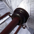 Close-up of the internal wooden mechanism and parasol spokes underneath the white fabric canopy.