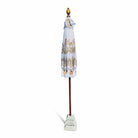 Closed white and gold Balinese parasol showing the folded fabric and carved decorative top finial.