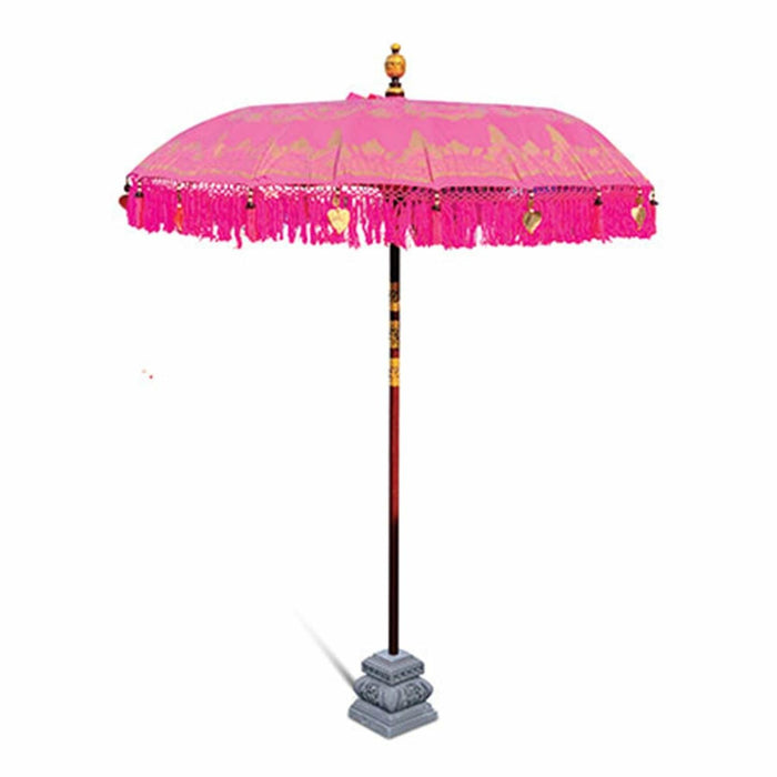 Vibrant pink Bali sun parasol with gold fringe and hand-painted details on a tall wooden pole