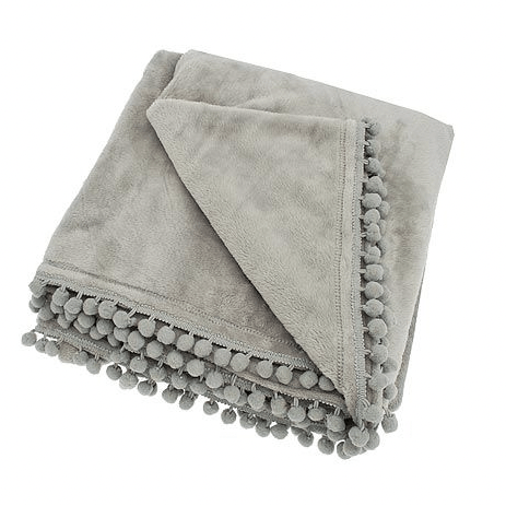 Folded grey cashmere-touch fleece throw with decorative pom-pom braid edge against a white background.