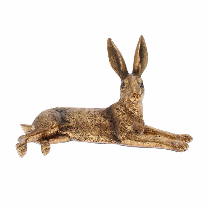 Golden effect resin hare sculpture in an outstretched lying pose against a white background.