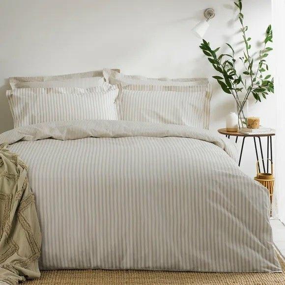 Hebden mélange stripe duvet cover set in natural, styled on a bed with matching pillowcases and a textured throw.
