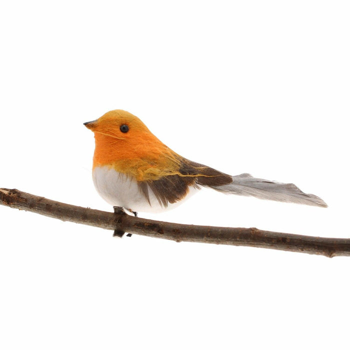 Side profile of a realistic feathered robin decoration perched on a thin brown branch.